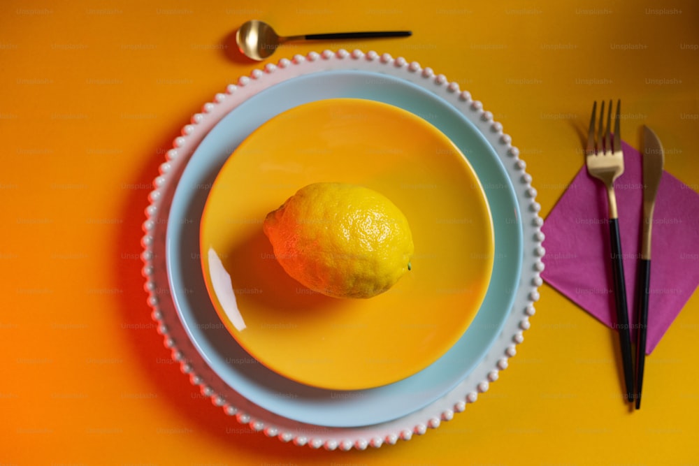 a plate with a lemon on it next to a fork and knife