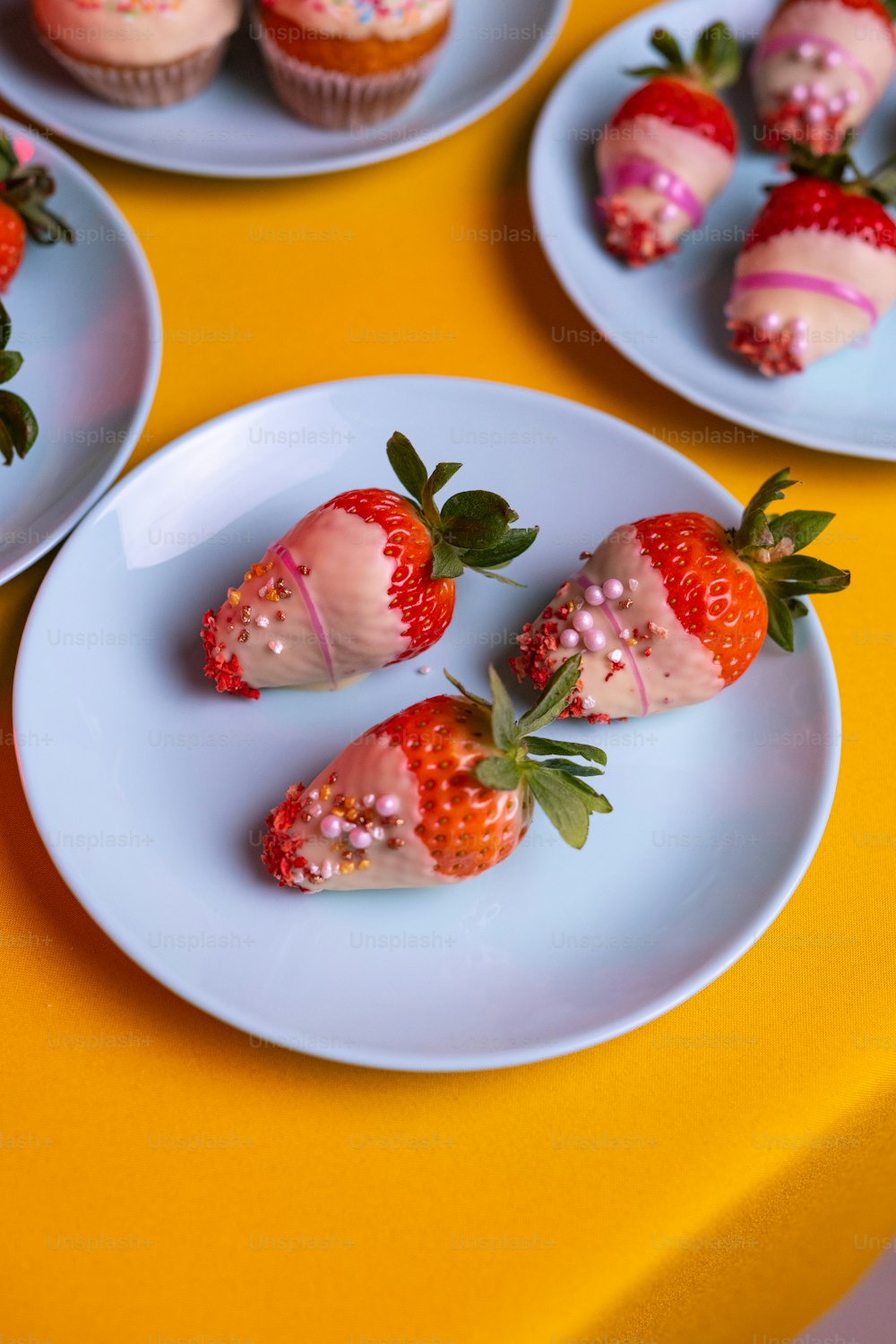 a table topped with plates of cupcakes and strawberries