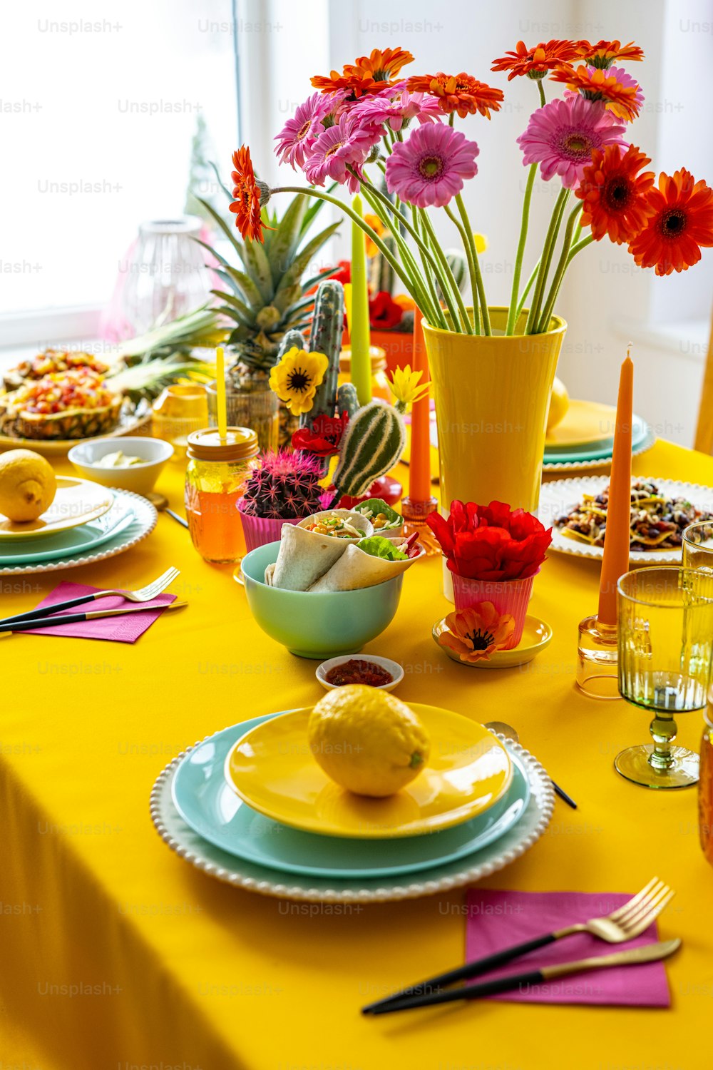 ein Tischset mit einer gelben Tischdecke und Tellern und Blumen