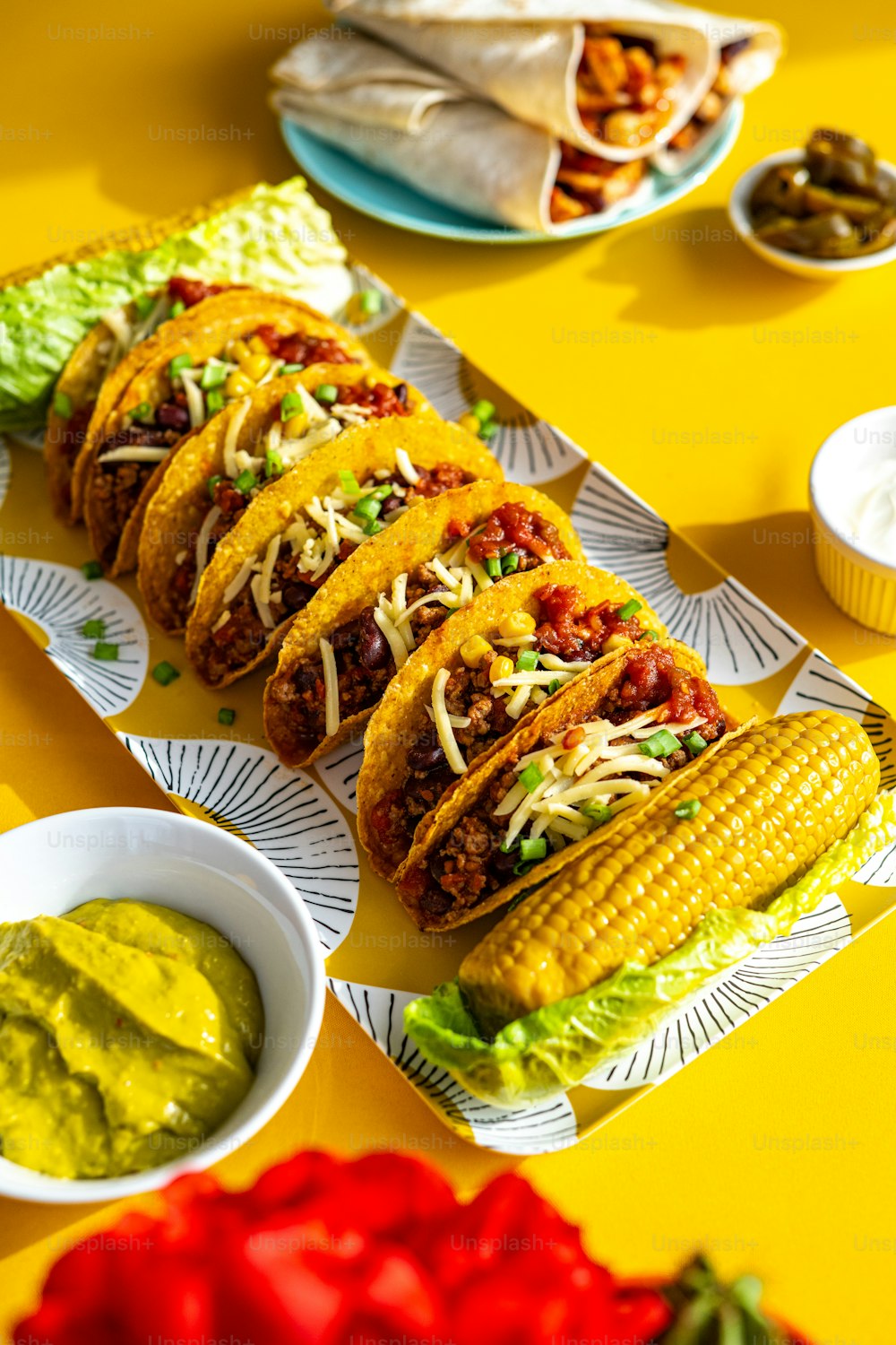 a table topped with plates of tacos and guacamole