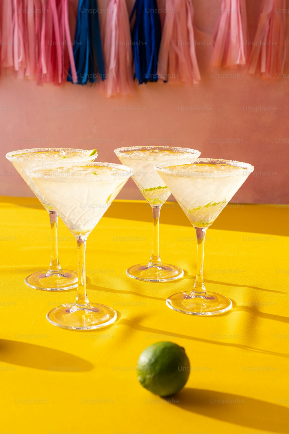 three martini glasses sitting on top of a yellow table