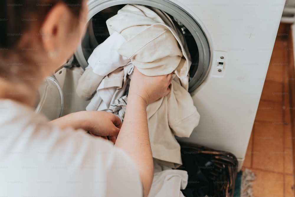 Una mujer está poniendo ropa en una lavadora