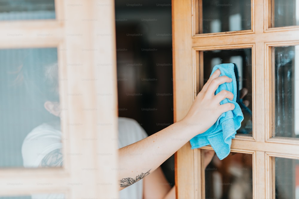 una persona limpiando una ventana con un paño