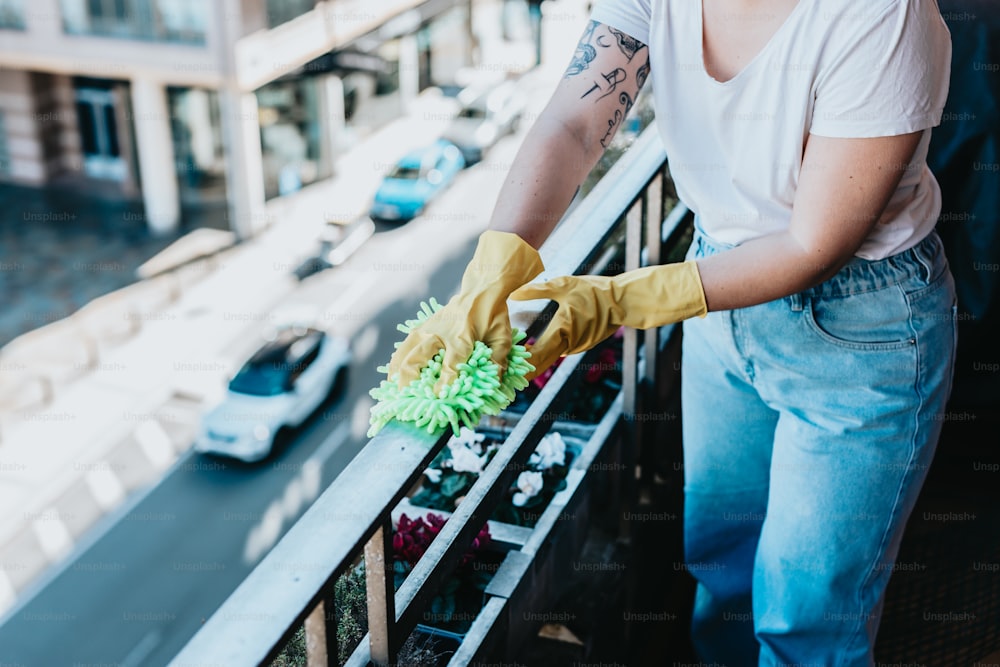 Una mujer con guantes amarillos está limpiando un balcón