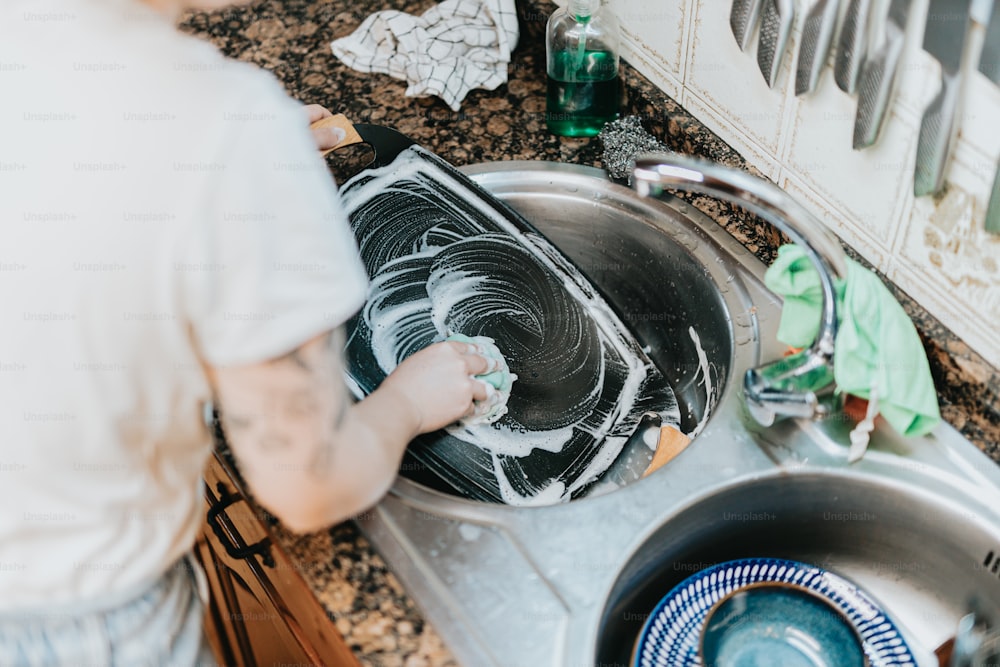 a man washing dishes in a kitchen sink