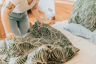 a woman standing over a bed with a green and white comforter