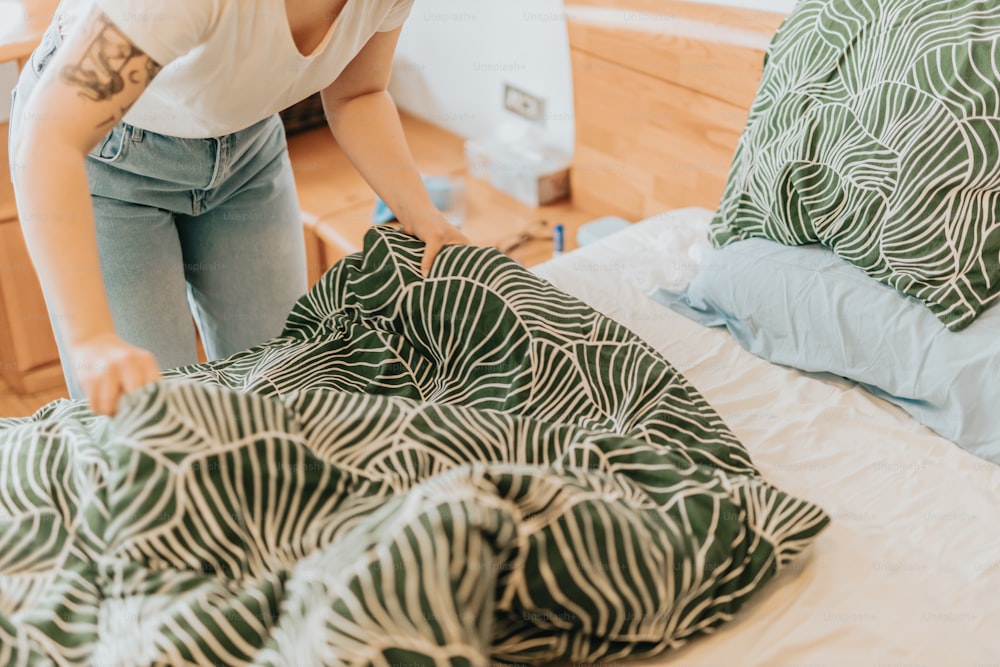 a woman standing over a bed with a green and white comforter