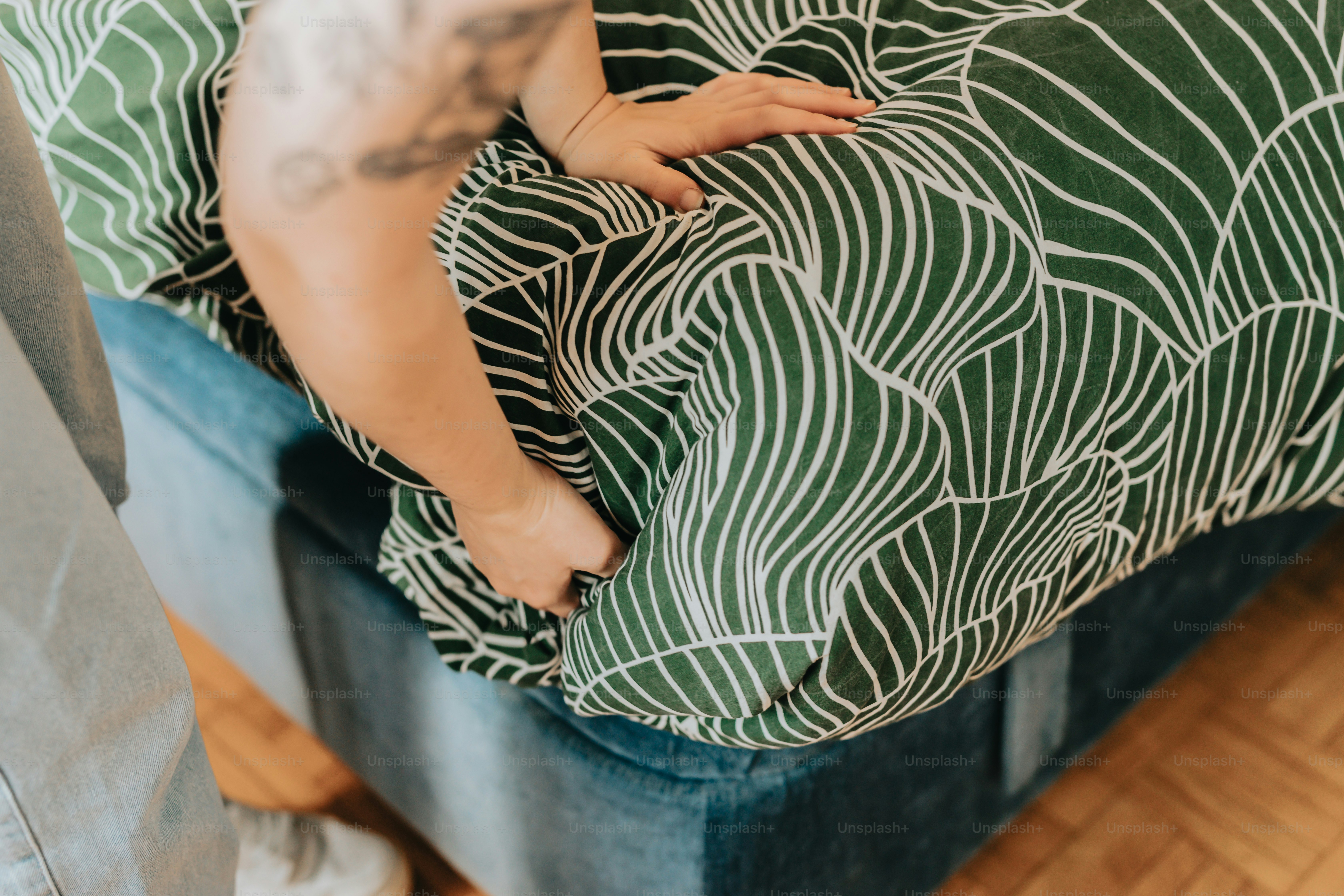 eine Person, die mit einem grün-weißen Kissen auf einer Couch steht