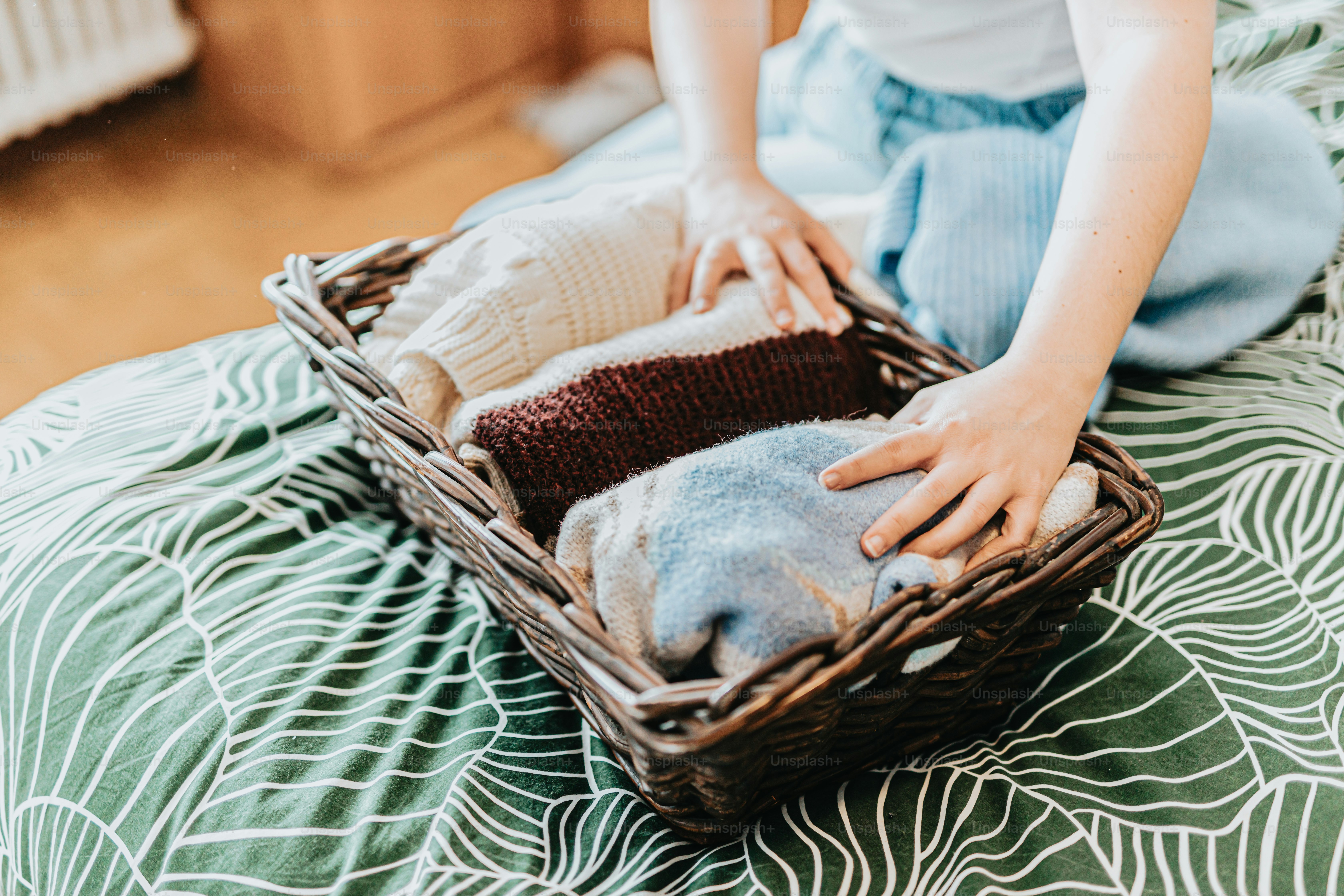 Eine Person, die auf einem Bett sitzt und einen Korb mit einem Stofftier darin hält