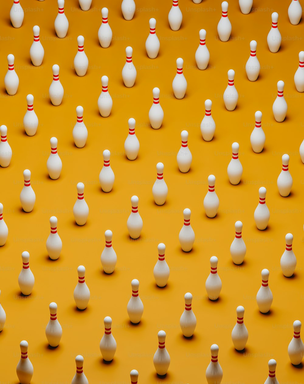 a large group of white bowling pins on a yellow background