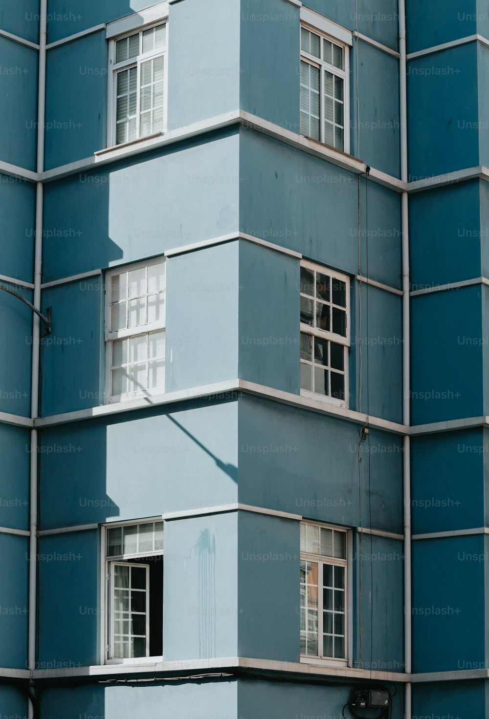 a tall blue building with windows and a street sign