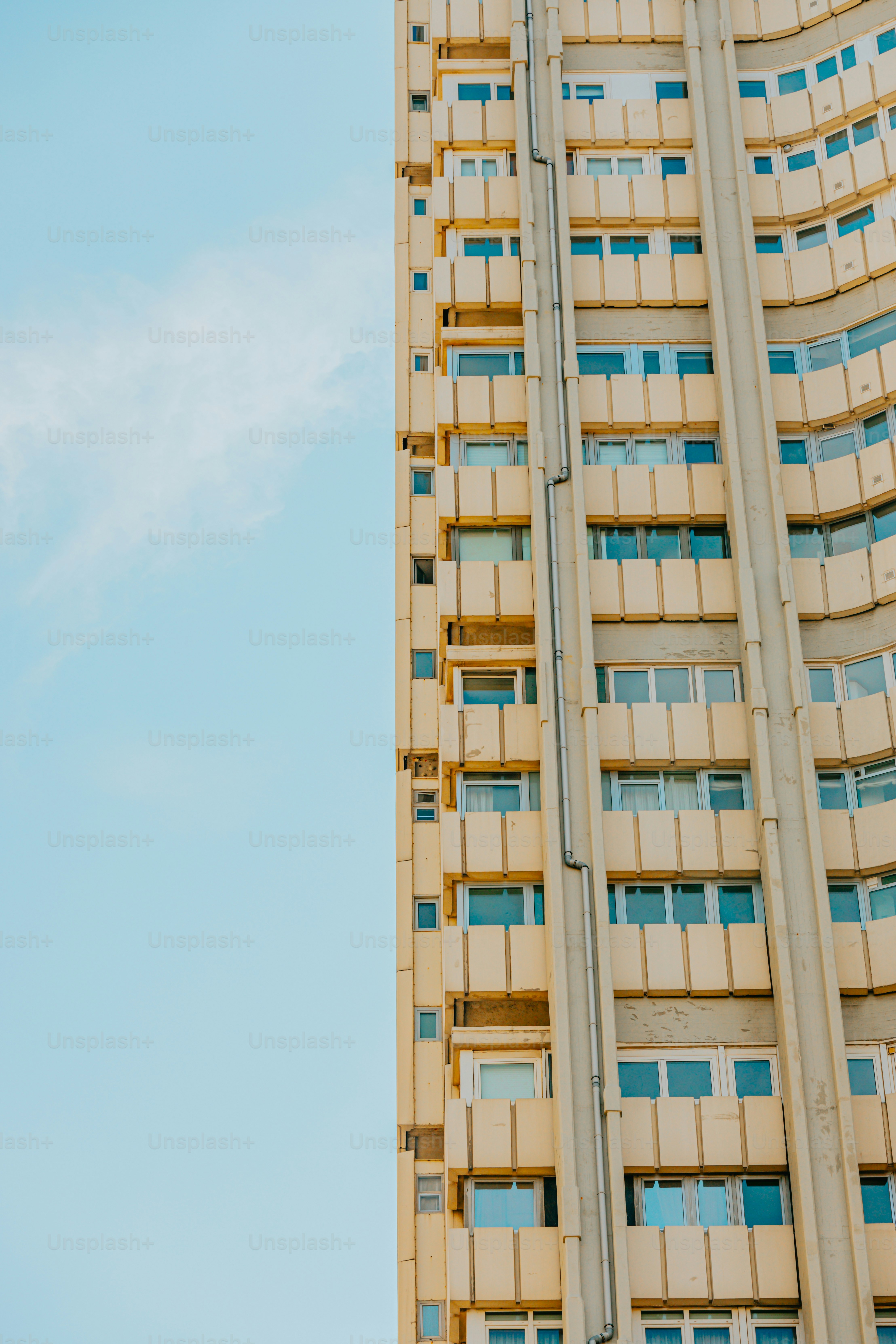 a tall building with windows and balconies against a blue sky