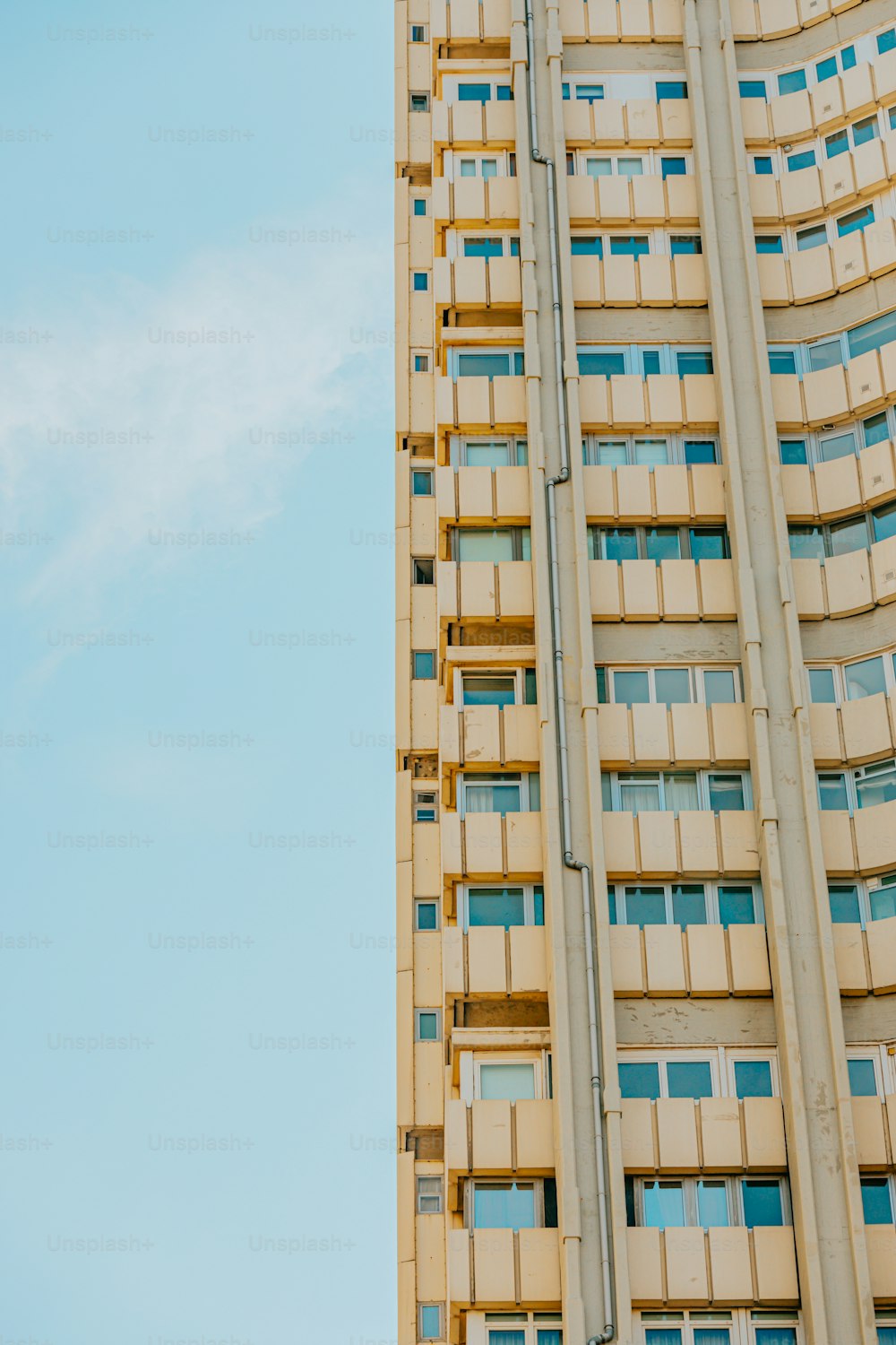 Ein hohes Gebäude mit Fenstern und Balkonen vor blauem Himmel