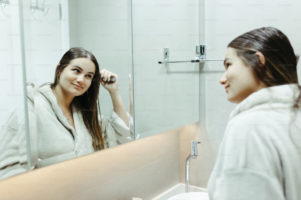 a woman brushing her hair in front of a mirror