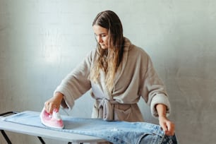 a woman ironing clothes on an ironing board