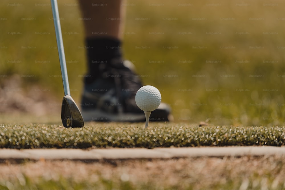 a person putting a golf ball on a tee