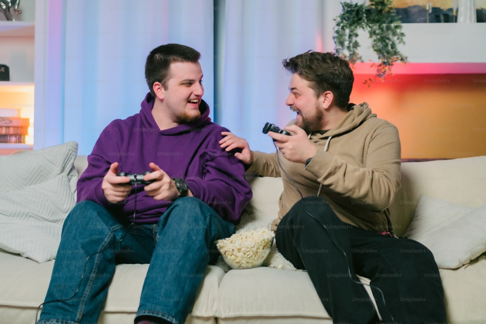 ソファに�座ってビデオゲームをしている2人の男性