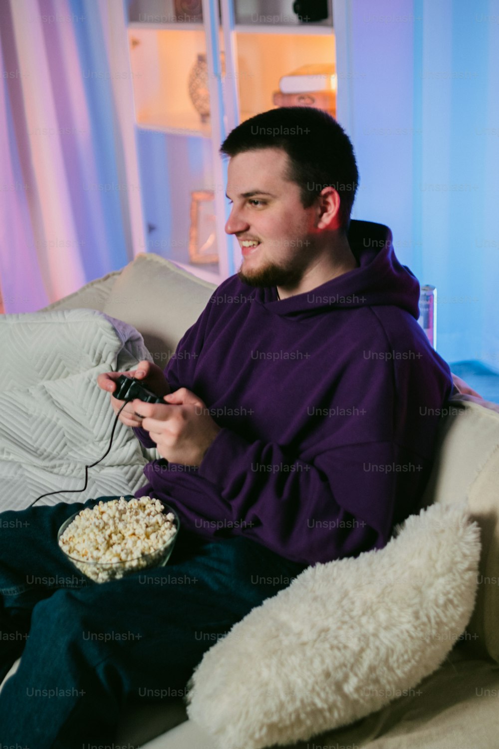 Ein Mann sitzt auf einer Couch mit einer Fernbedienung und einer Schüssel Popcorn