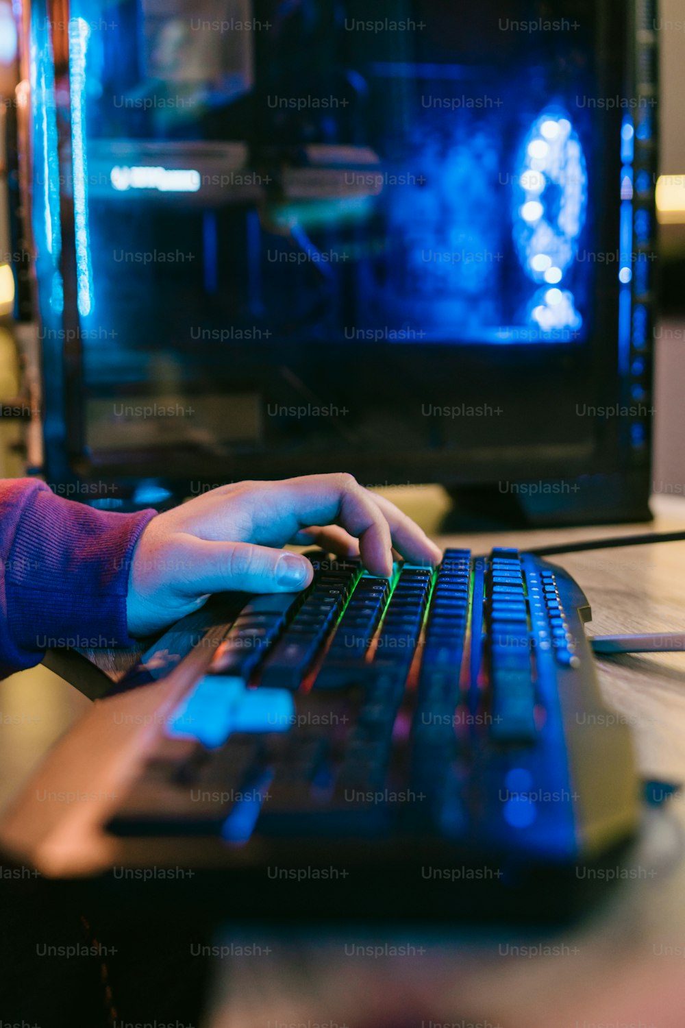 a person typing on a computer keyboard in front of a television