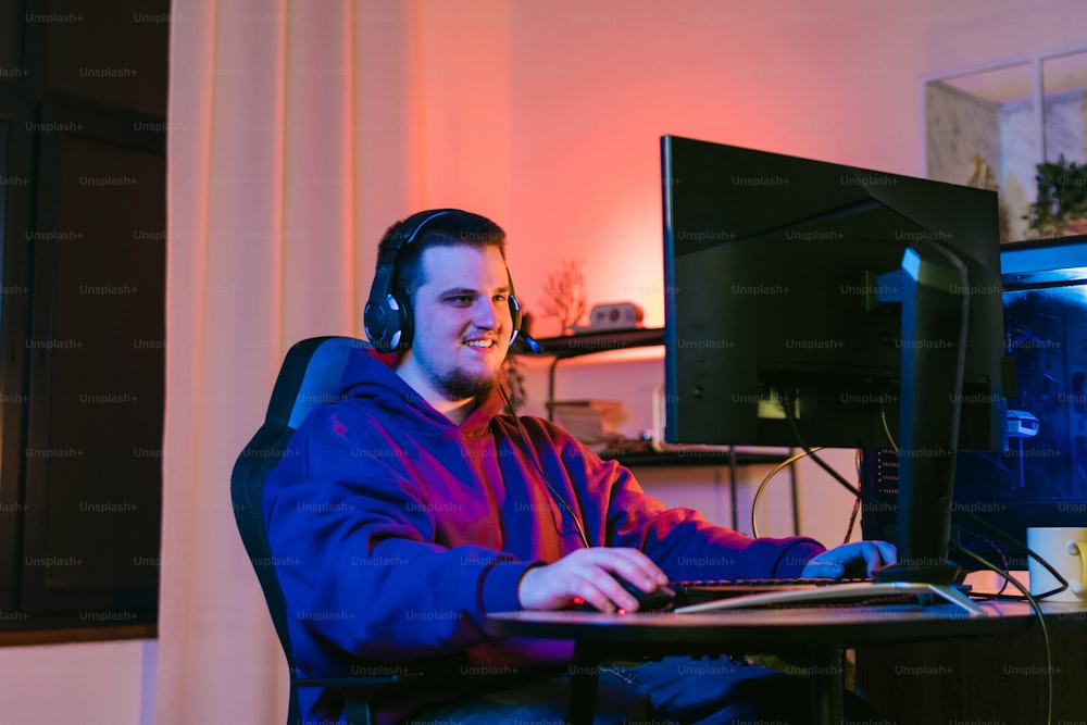 Un uomo che indossa le cuffie seduto davanti a un computer