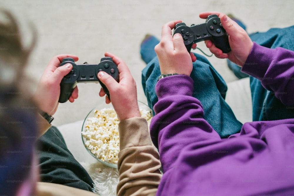 Due persone sedute su un divano che giocano a un videogioco
