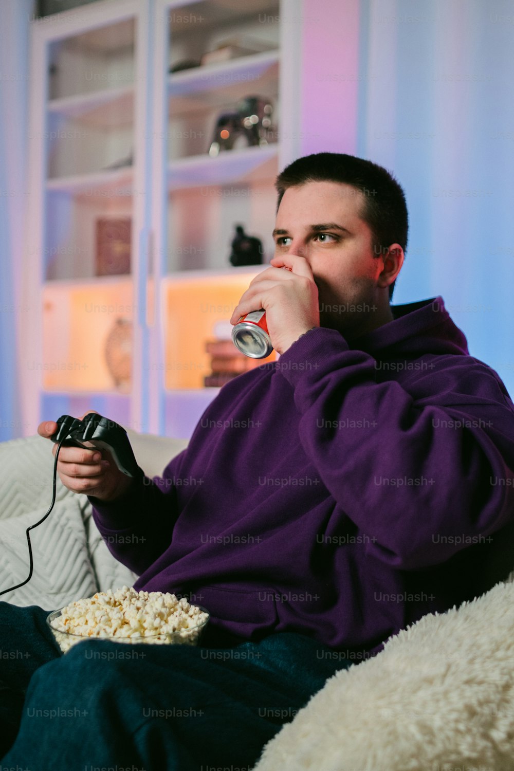 a man sitting on a couch drinking from a can