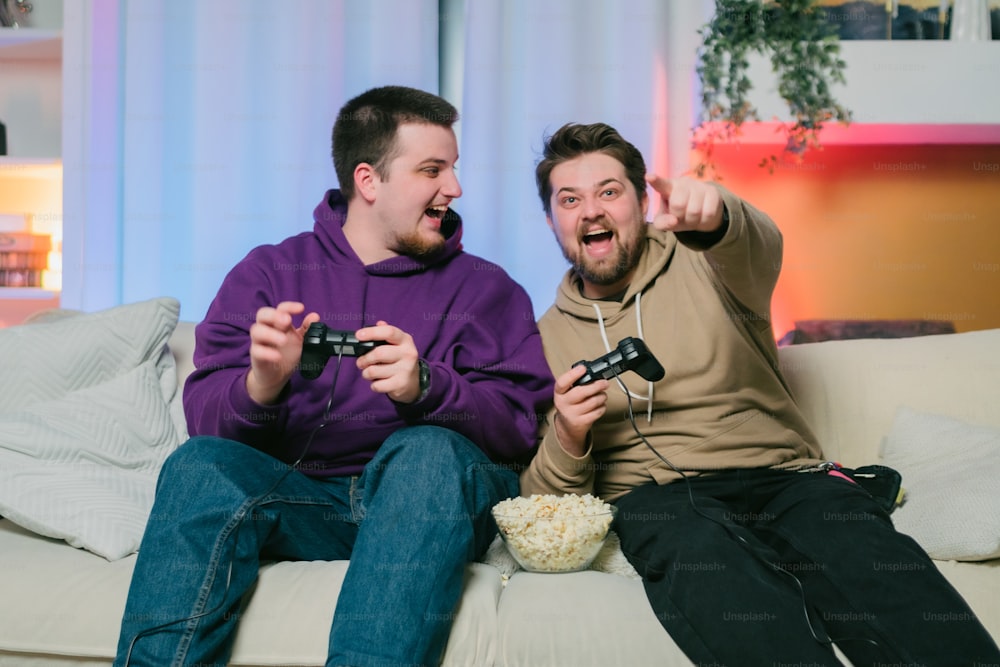 Dos hombres sentados en un sofá jugando un videojuego