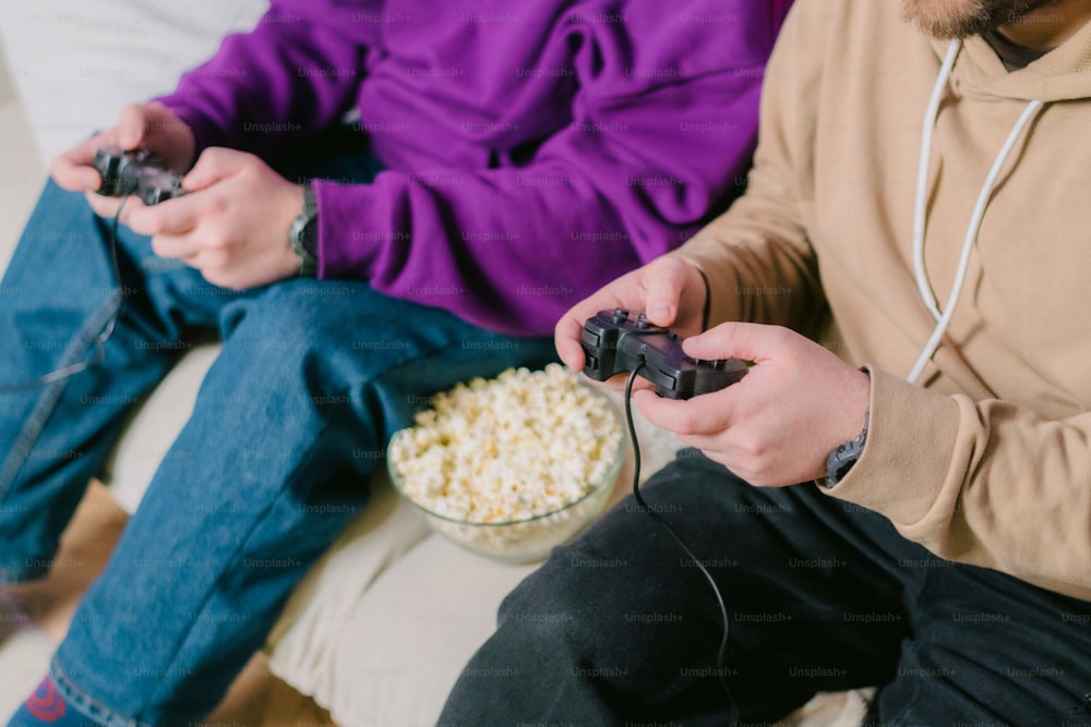 Zwei Personen sitzen auf einer Couch und spielen Videospiele