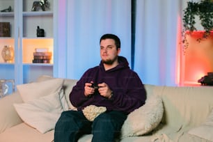 a man sitting on a couch holding a remote control