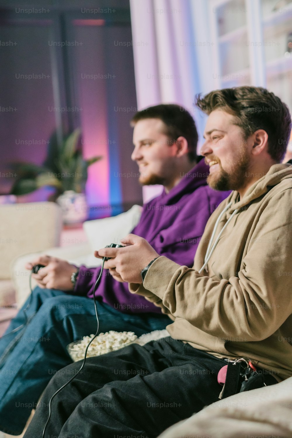 Zwei Männer sitzen auf einer Couch und spielen ein Videospiel