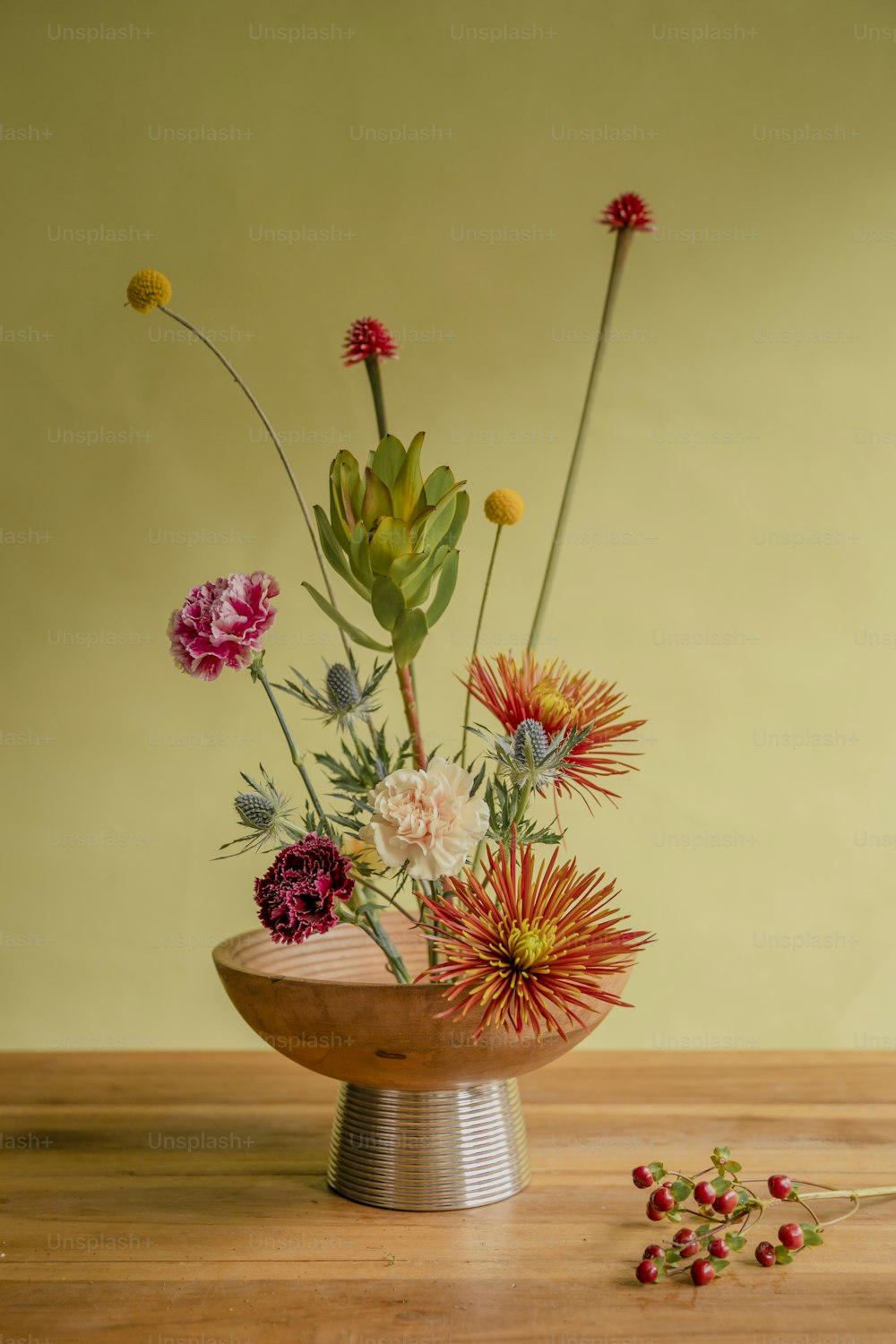 a wooden bowl filled with flowers on top of a wooden table