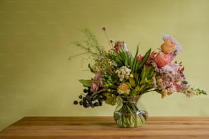 Un jarrón lleno de muchas flores encima de una mesa de madera