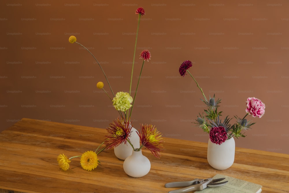 a wooden table topped with three vases filled with flowers