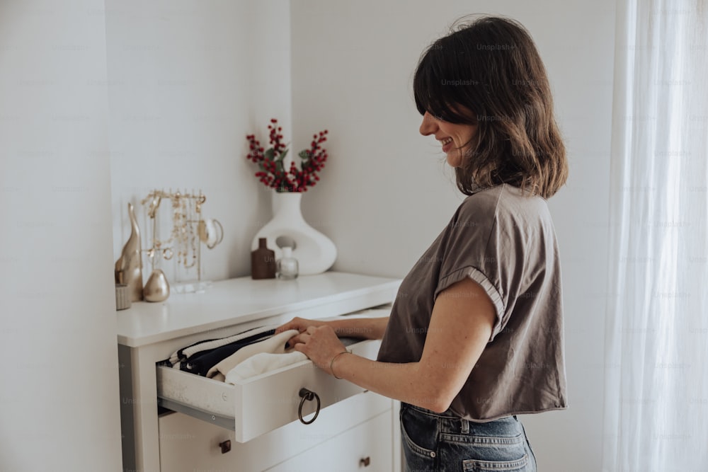 a woman opening a drawer in a white room