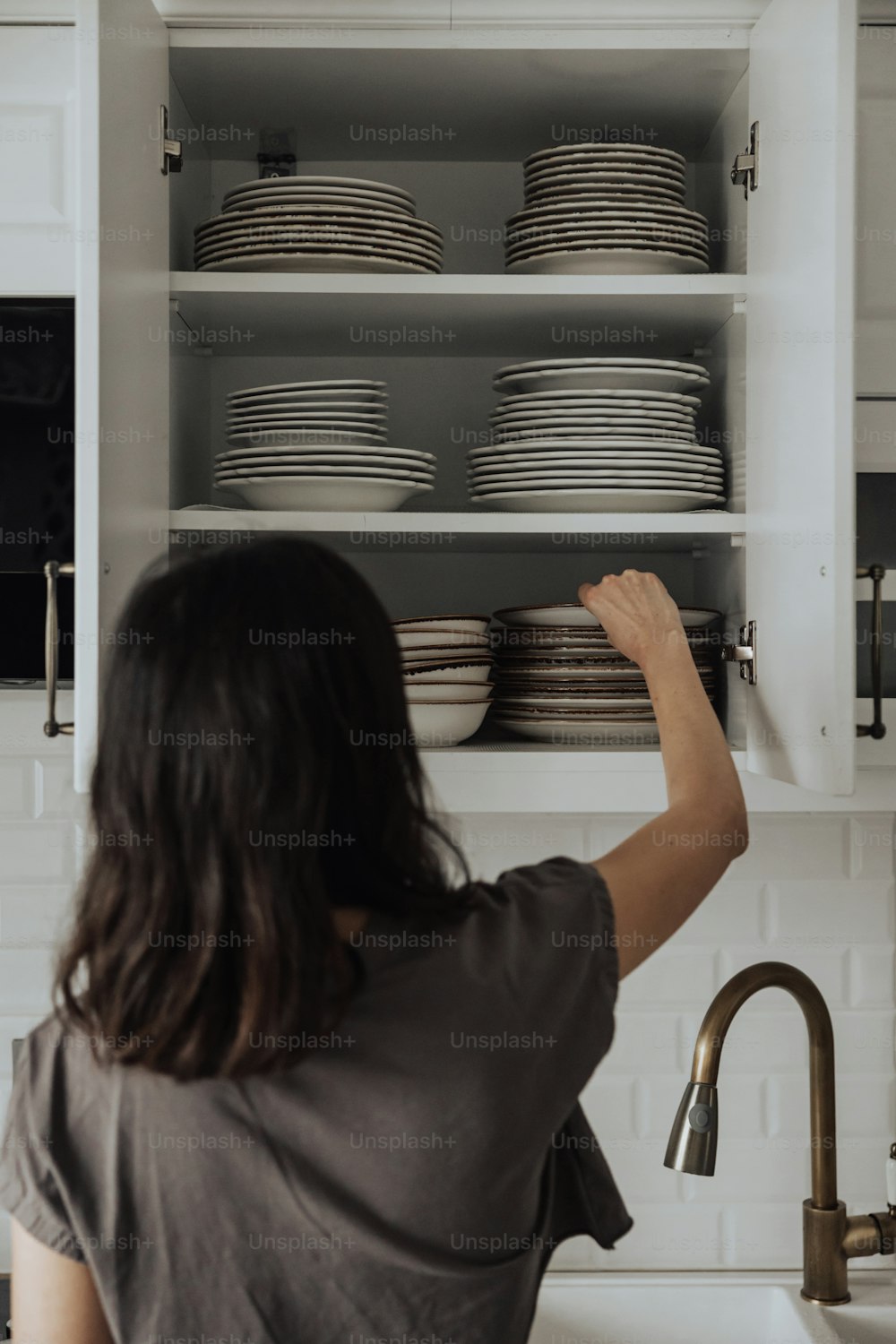 Una mujer está poniendo platos en un armario