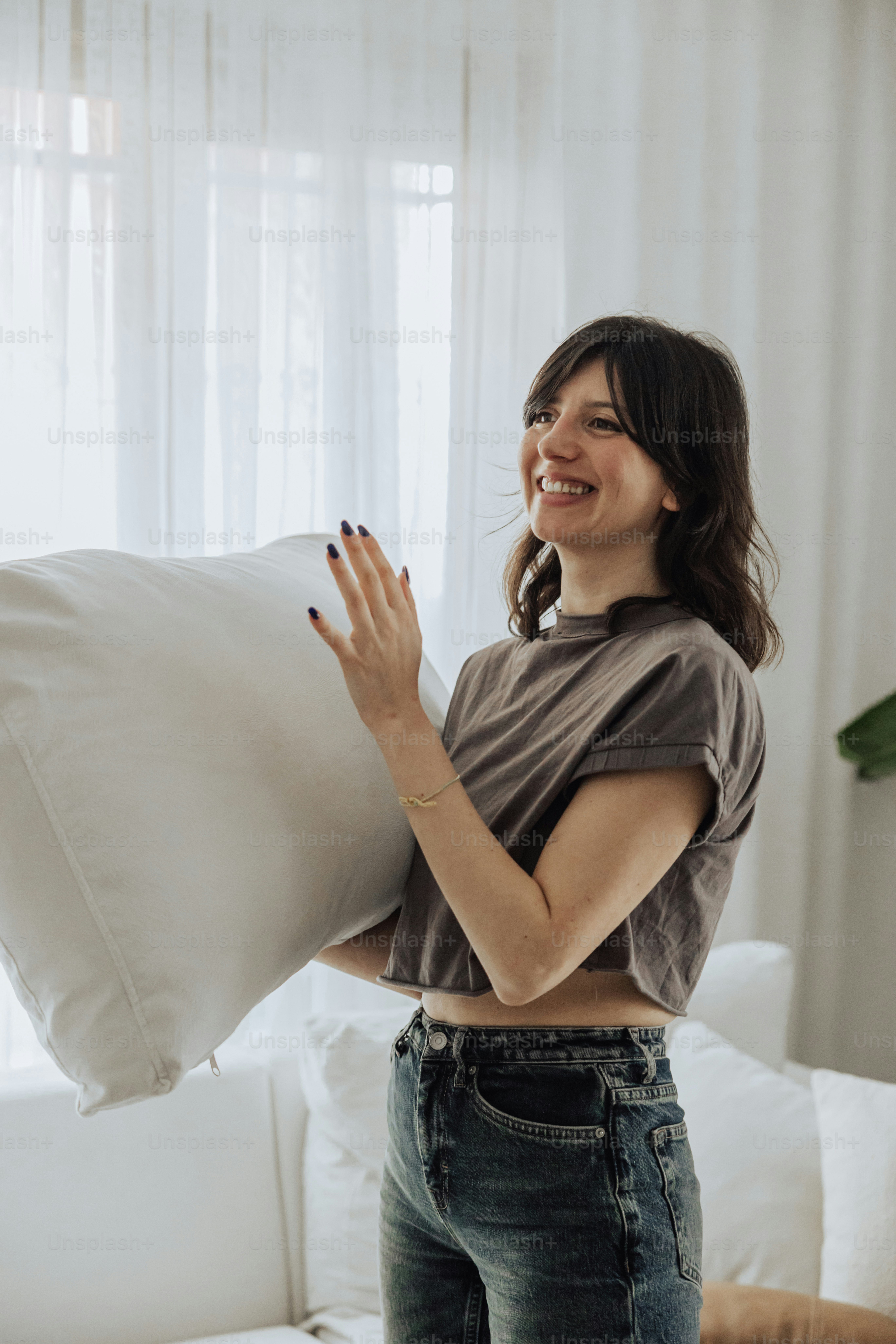 a woman holding a pillow and smiling at the camera