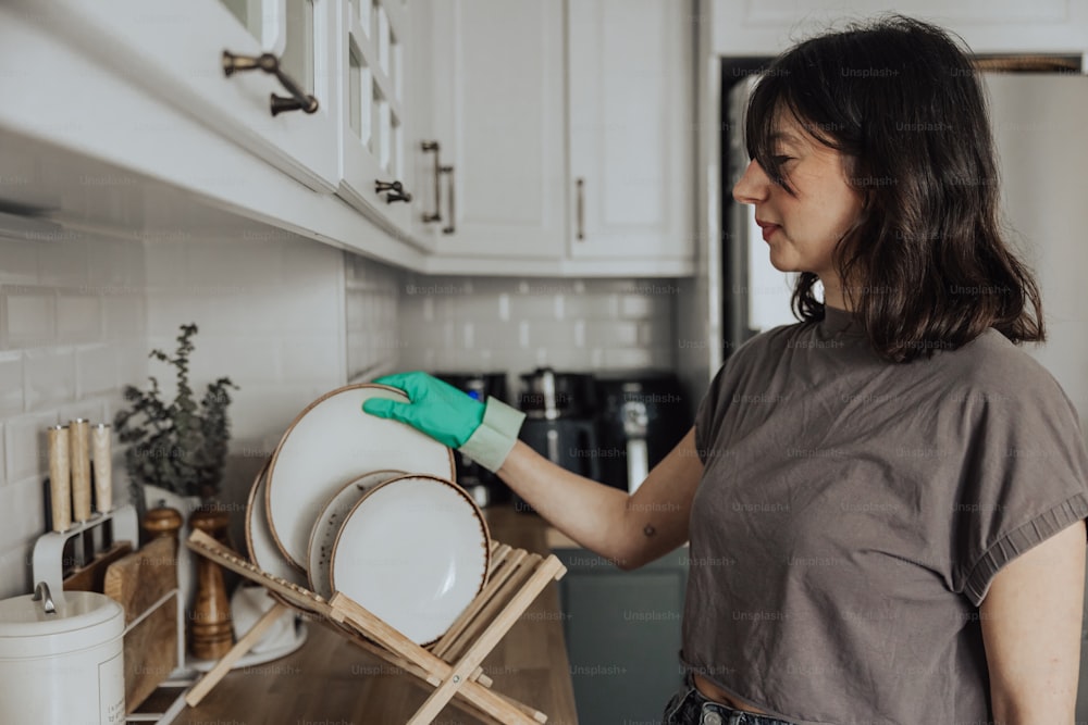 Una donna in una cucina con in mano una lavastoviglie