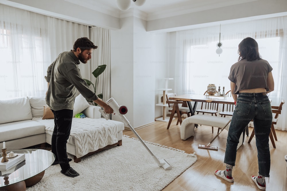 Un hombre y una mujer están limpiando una sala de estar juntos
