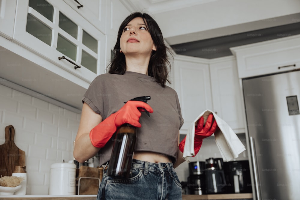 a woman standing in a kitchen holding a bottle