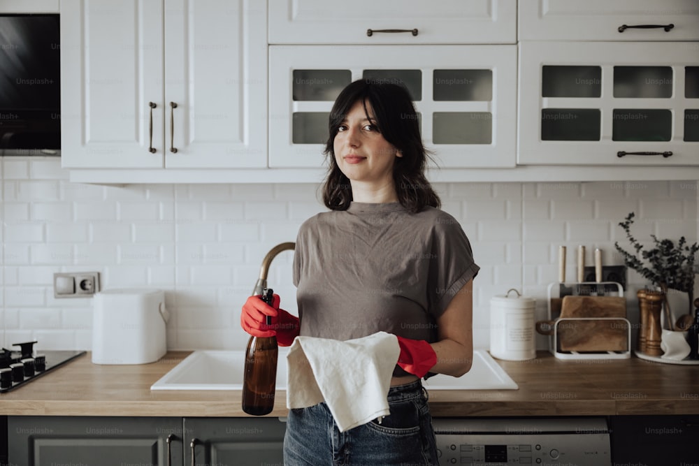 a woman standing in a kitchen holding a paper towel
