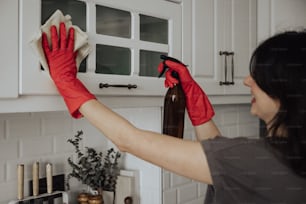 a woman cleaning a kitchen counter with red gloves