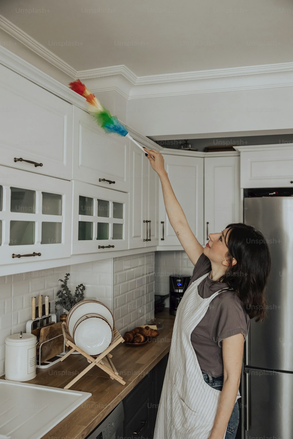 Une femme nettoyant une cuisine avec une brosse colorée