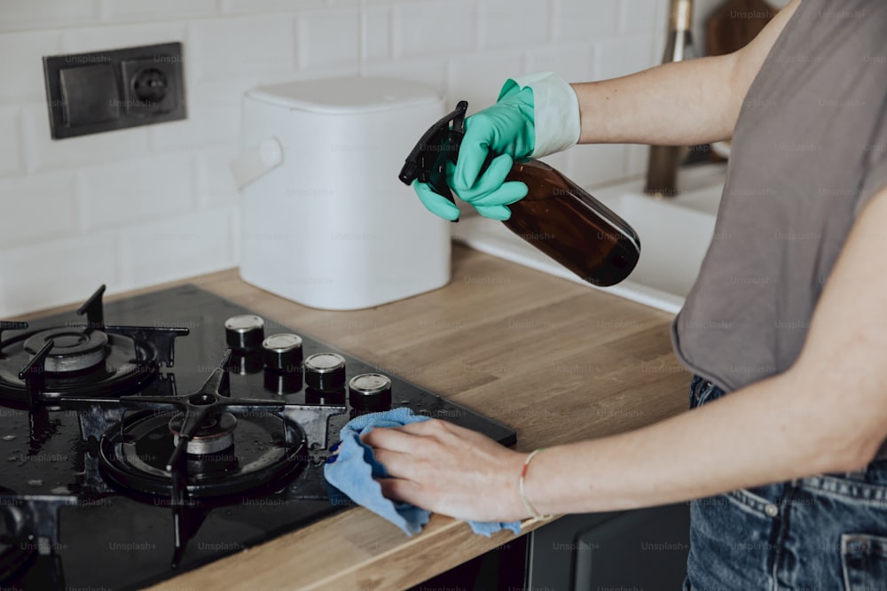 a woman cleaning a stove top with a rag