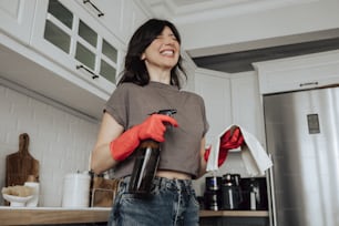a woman standing in a kitchen holding a bottle