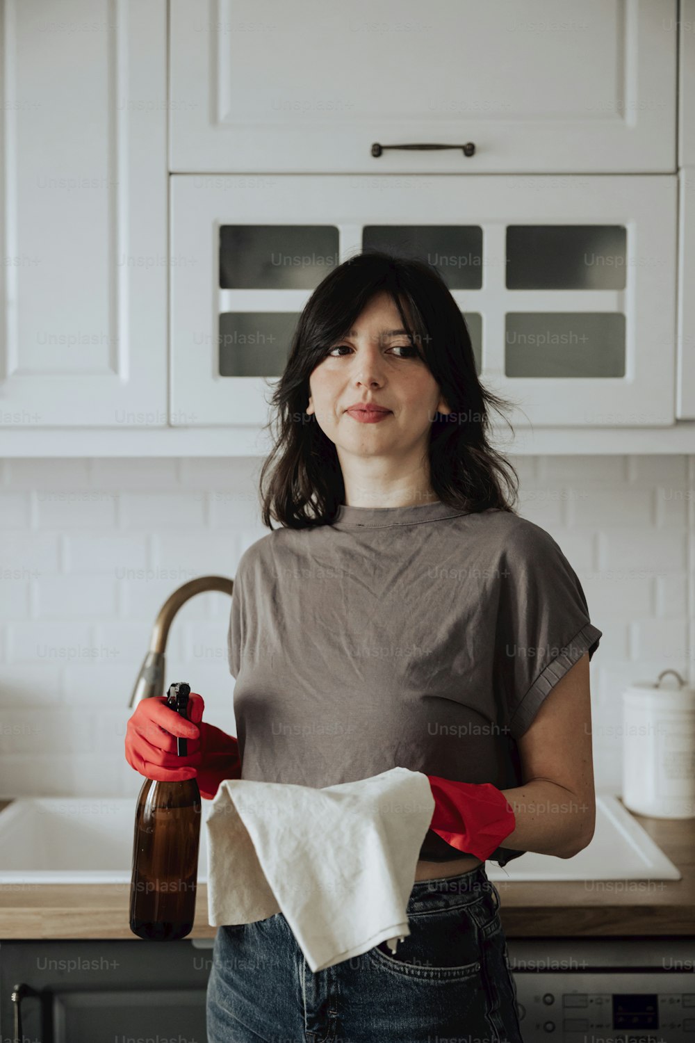 Une femme debout dans une cuisine tenant une bouteille