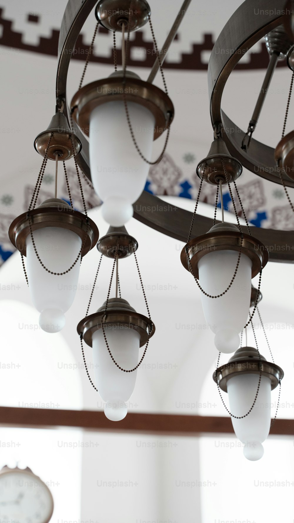 a chandelier hanging from a ceiling with a clock in the background