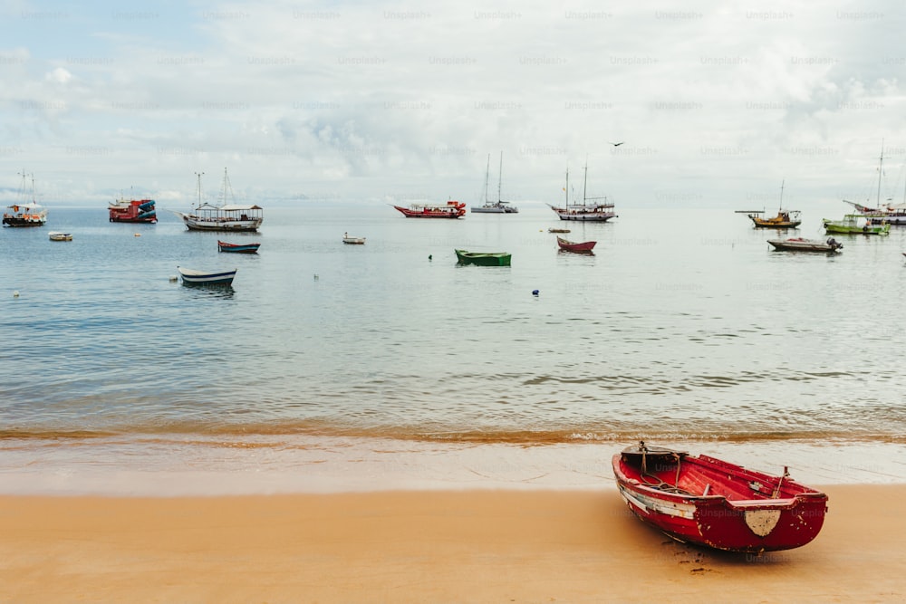 a red boat sitting on top of a sandy beach