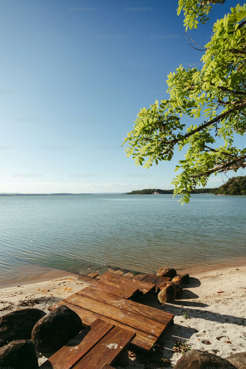 a wooden bench sitting on top of a sandy beach