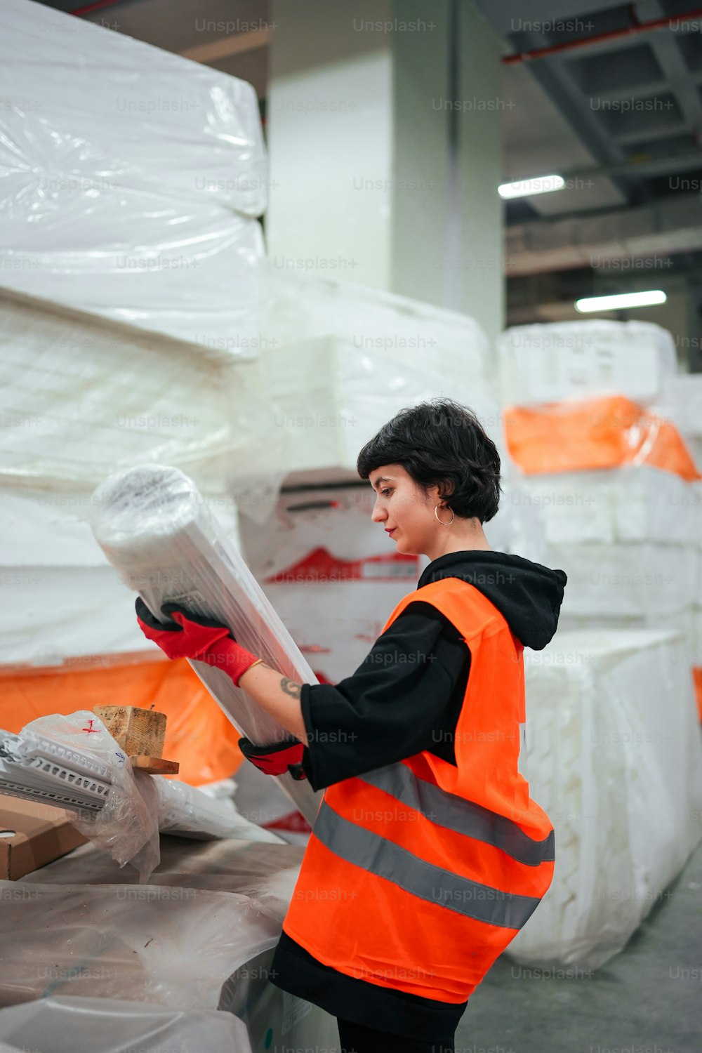 a woman in an orange vest is working in a warehouse