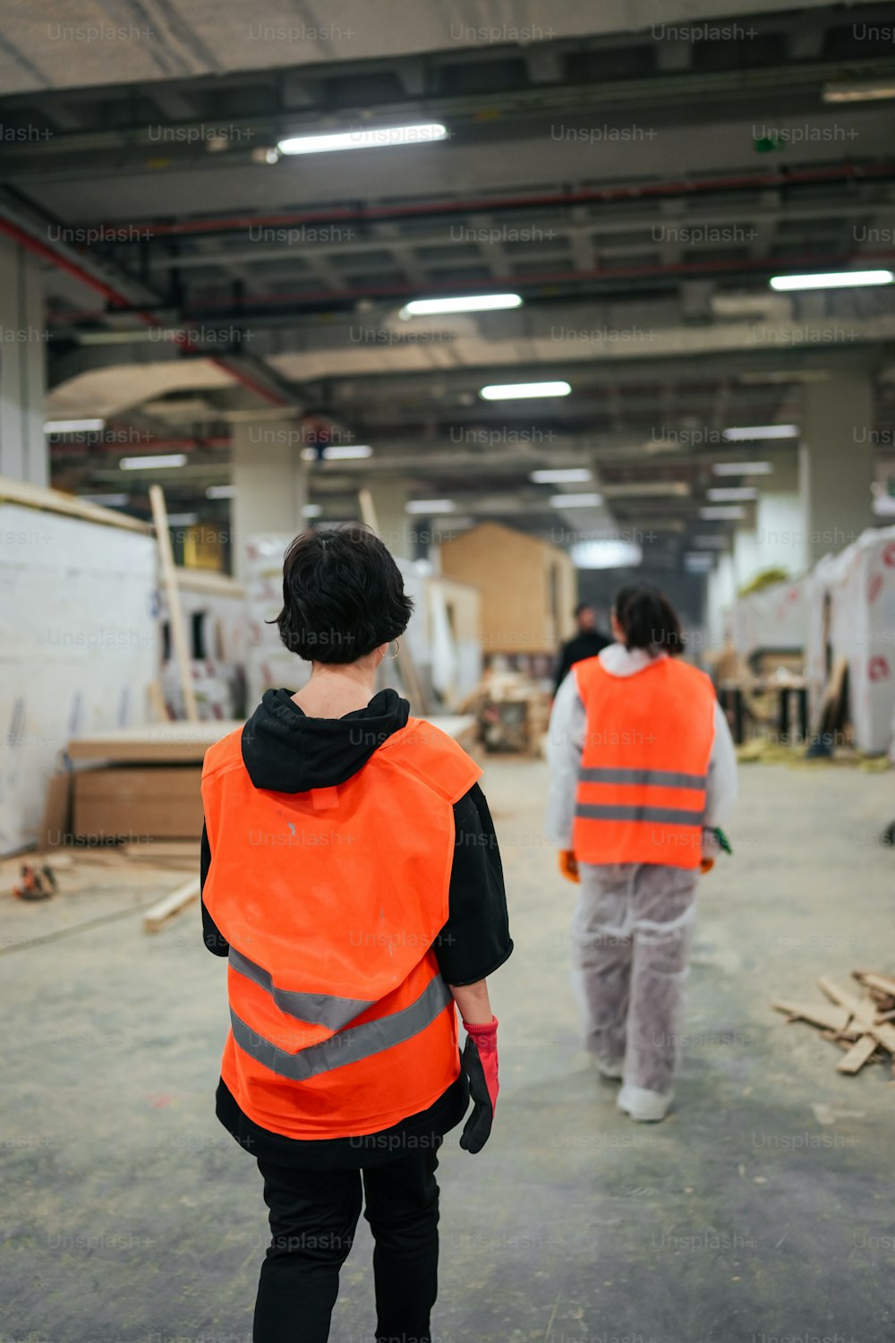 two people in orange vests walking in a warehouse